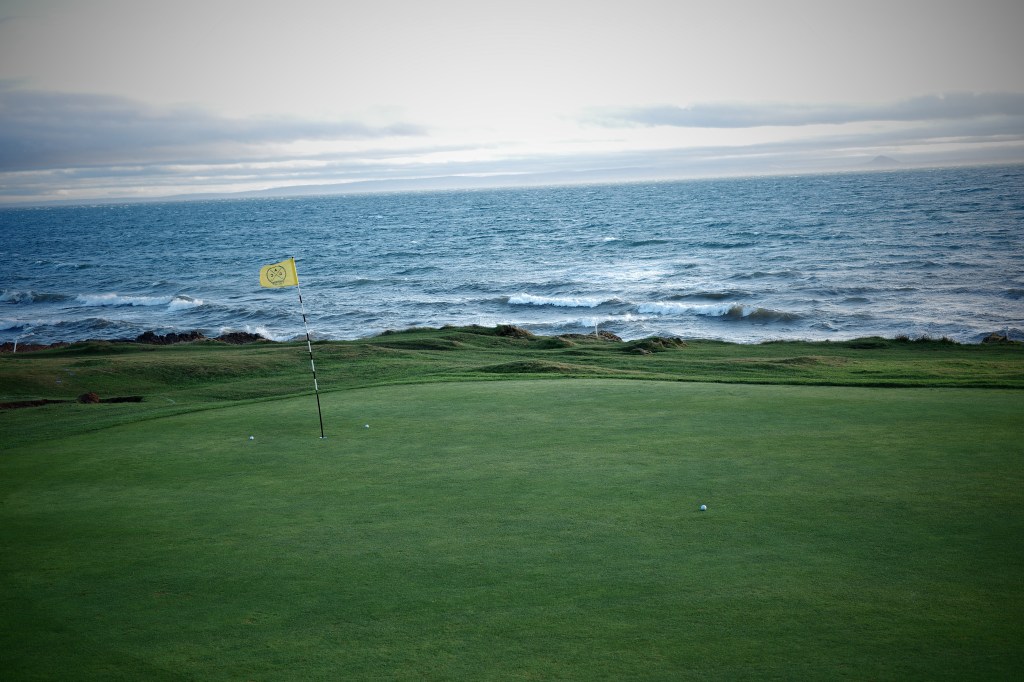 View of a golf green near the ocean.